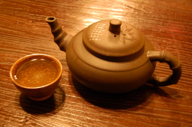 Cup_of_green_tea_and_tea_pot_on_table